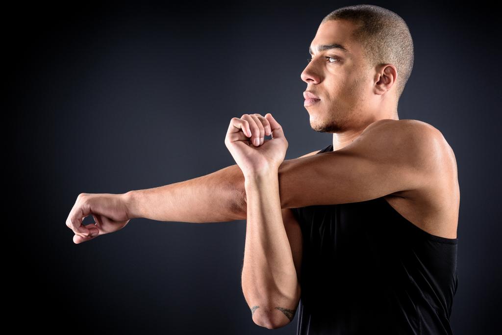 young african american sportsman stretching arms on black - Photo, Image