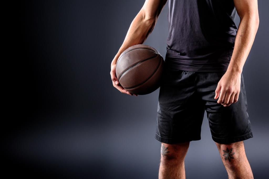cropped shot of basketball player holding ball on black - Photo, Image