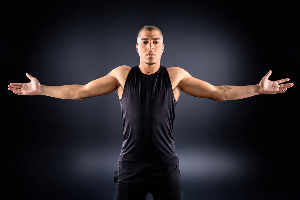 Afro-Amerikaanse sportman met uitgestrekte armen op zwart - Foto, afbeelding