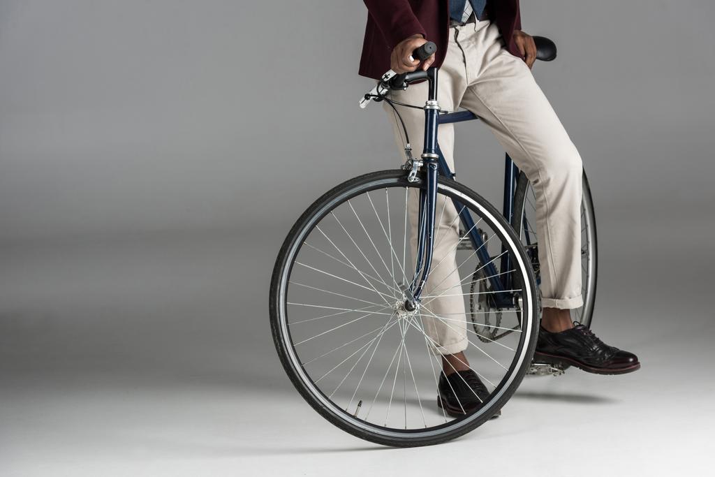 Section basse de l'homme assis sur un vélo sur fond gris
  - Photo, image