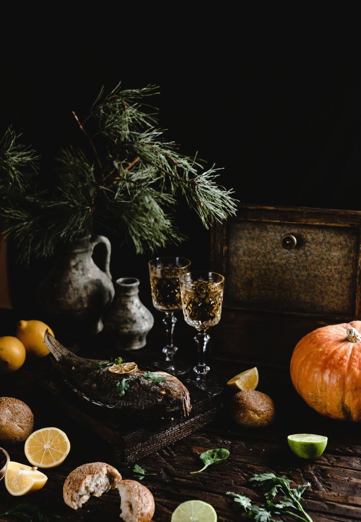 レモンと白ワイングラス暗い木製のテーブルの上に木の板にハーブで焼いた魚 - 写真・画像