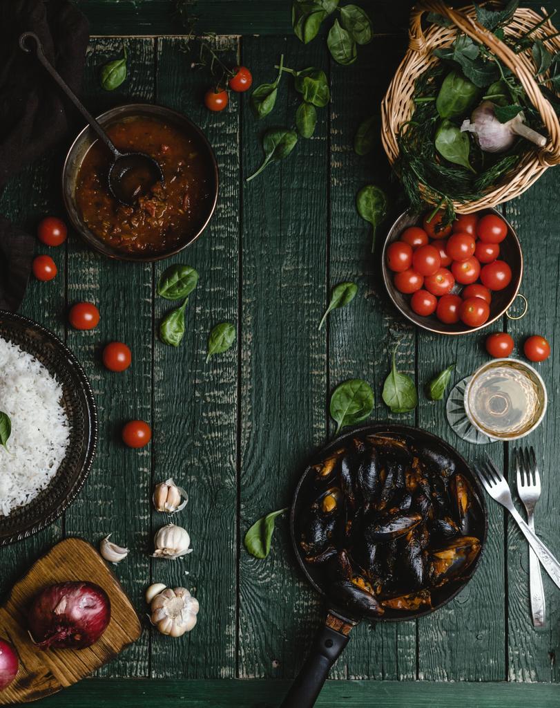 Vista superior de mexilhões cozidos com conchas servidas em panela com tomate, ervas e vinho em mesa rústica
 - Foto, Imagem