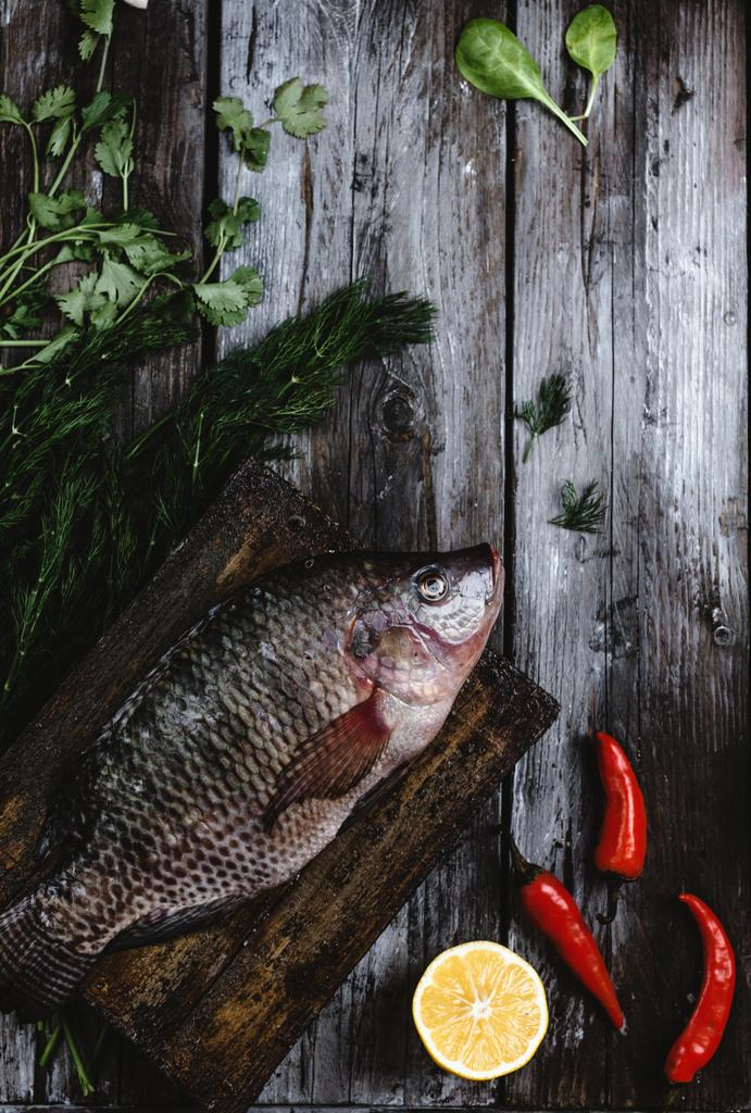 вид свежей сырой морской рыбы с травами и перцем чили на деревенском деревянном столе
 - Фото, изображение