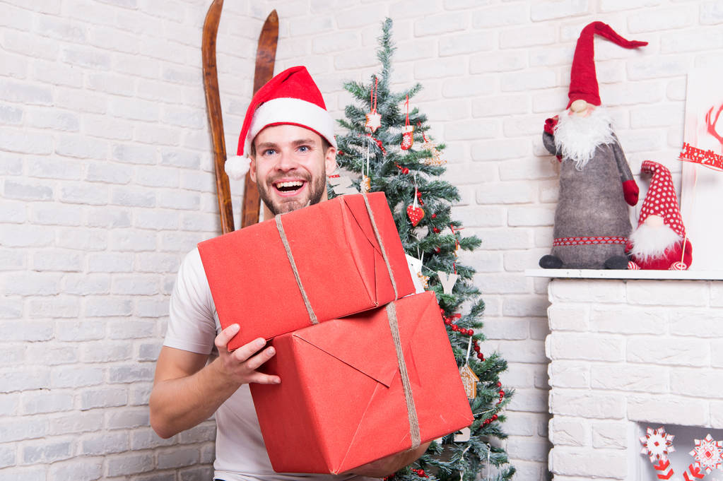 Kerst macho in rode hoed glimlach met ingepakte cadeautjes - Foto, afbeelding