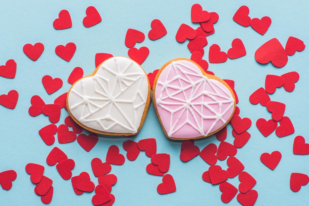 κάτοψη του καρδιά σχήμα cookies και κόκκινα διακοσμητικά κομφετί που απομονώνονται σε μπλε - Φωτογραφία, εικόνα