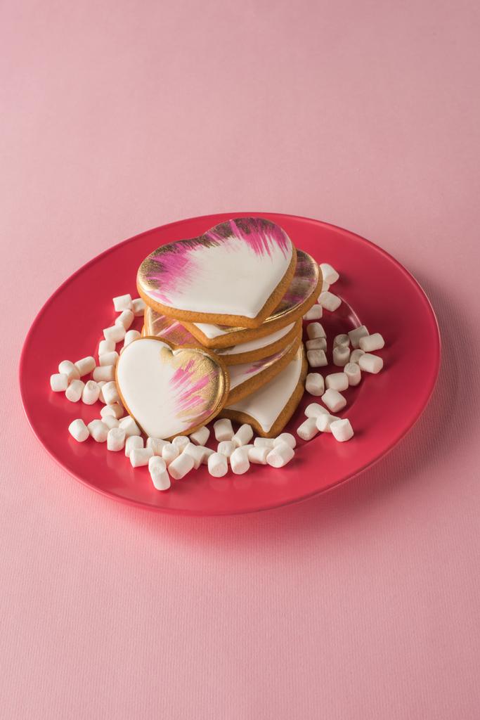 vista de cerca de las galletas en forma de corazón y malvavisco en la placa aislada en rosa
 - Foto, Imagen