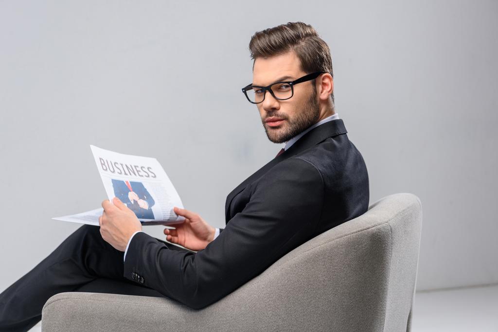 Geschäftsmann sitzt im Sessel und hält Zeitung - Foto, Bild