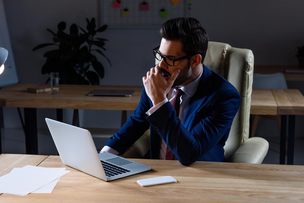 hombre de negocios serio sentado en la oficina oscura y bostezando
 - Foto, imagen