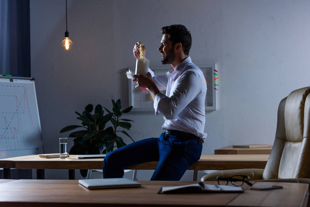 голодный бизнесмен ест лапшу с палочками в офисе
 - Фото, изображение