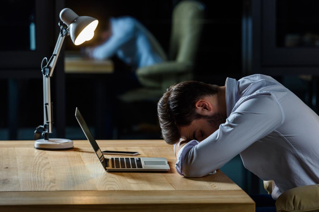 vista lateral do homem de negócios cansado dormindo à mesa com laptop
 - Foto, Imagem