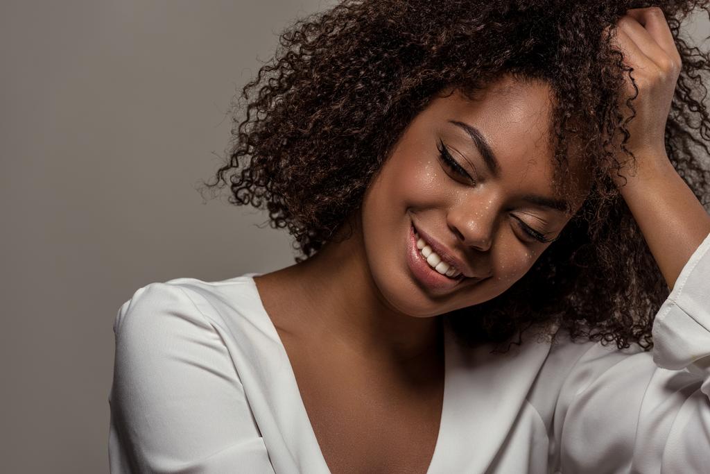 Giovane donna afroamericana sensuale in camicia bianca poggia sulla mano isolata su sfondo grigio
 - Foto, immagini