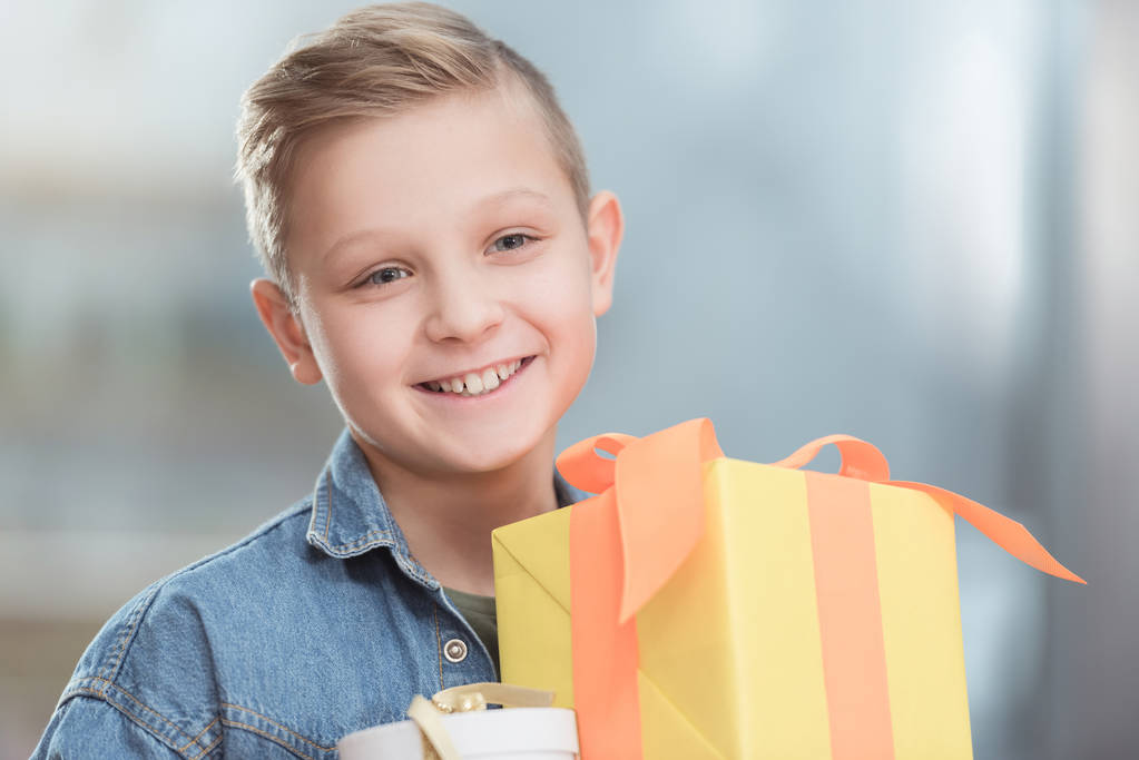 smiling boy holding stacked boxes at shop    - Photo, Image