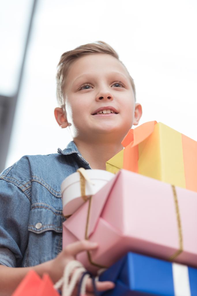 uśmiechnięty chłopiec trzyma poukładane pudełka z torby papierowe w ręce w sklepie   - Zdjęcie, obraz