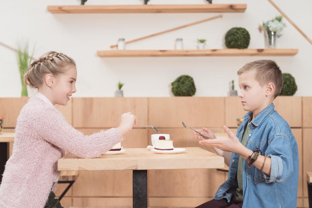 дети сидят за столом в кафе и смотрят друг на друга
   - Фото, изображение