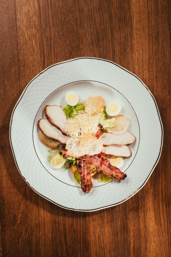 vista di fette di prosciutto con carne fritta e alcune uova sode sul piatto su superficie di legno
  - Foto, immagini