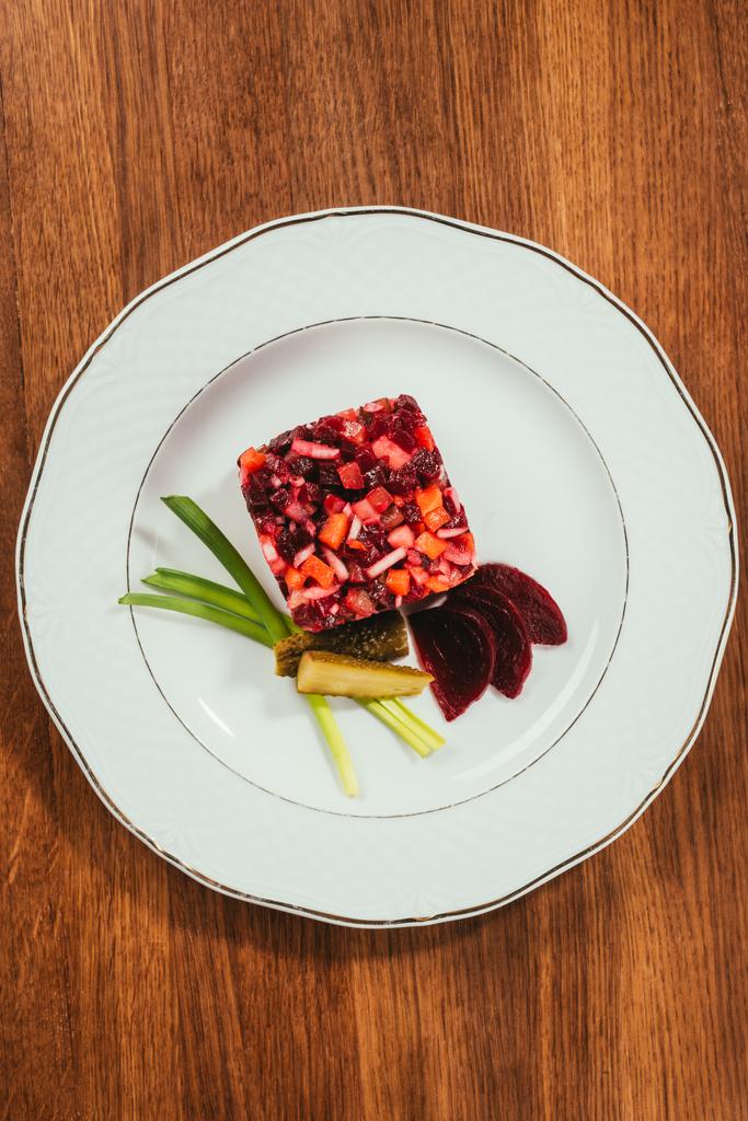 Vista dall'alto dell'insalata Acegret servita con cipolla verde e cetriolo sottaceto su piatto bianco su tavolo di legno
 - Foto, immagini