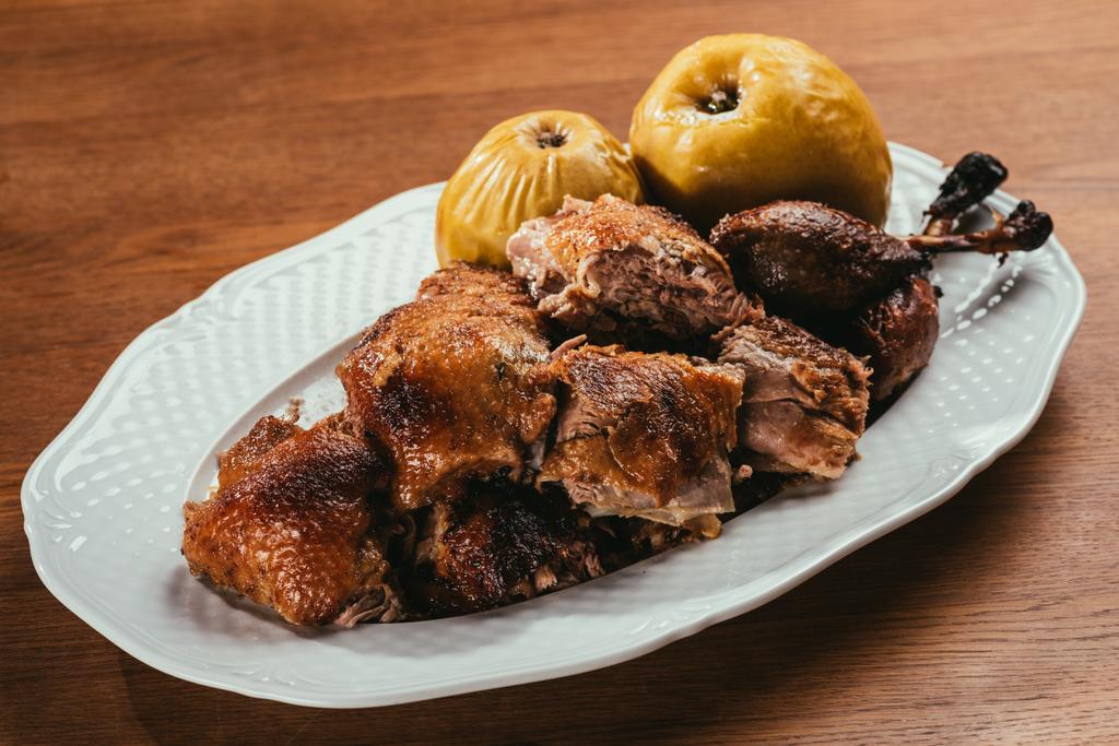 trozos de pato frito colocados en el plato con manzanas marinadas sobre una mesa de madera
  - Foto, imagen