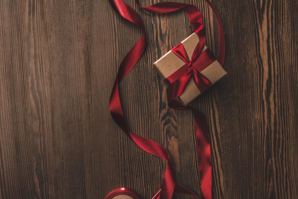 flat lay with present and red ribbon on wooden tabletop - Photo, Image
