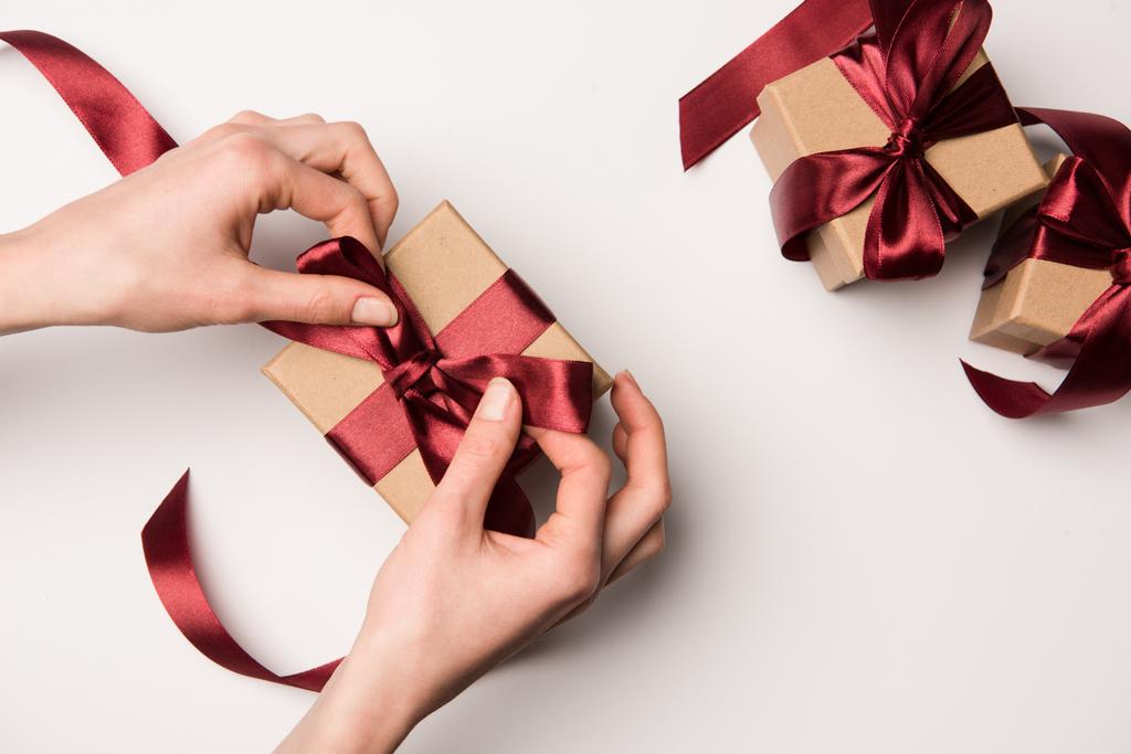vista parcial de la mujer atando cinta en caja de regalo aislado en blanco
 - Foto, imagen