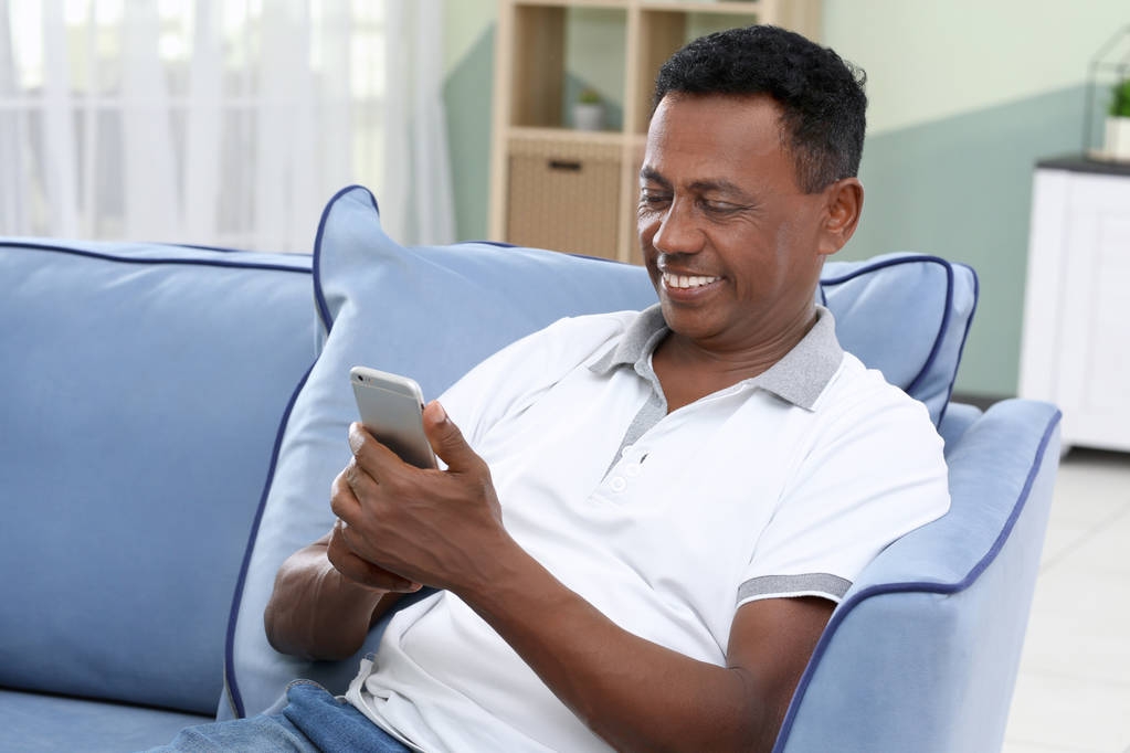 Homme mûr afro-américain utilisant un téléphone portable à la maison
 - Photo, image