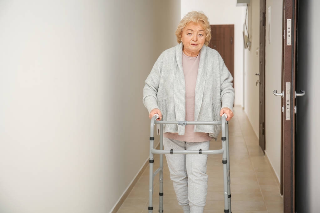 Пожилая женщина с ходячей рамой в коридоре
 - Фото, изображение