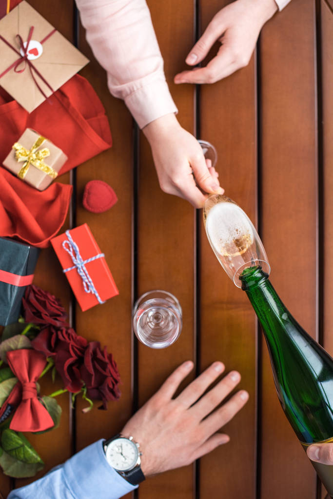 abgeschnittenes Bild eines Mannes, der Champagner in Freundin-Glas gießt - Foto, Bild