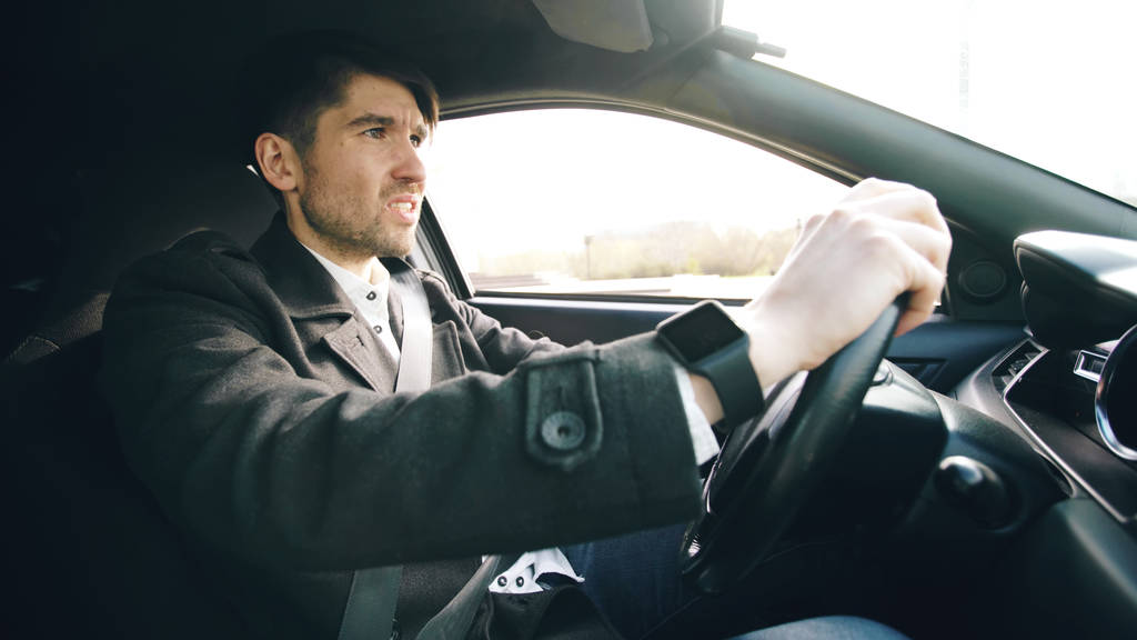 Νέοι επαγγελματίες άνθρωπος οδήγηση αυτοκινήτου πολύ αναστατωμένος και τόνισε μετά από σκληρή αποτυχία και κινείται σε κυκλοφορία μαρμελάδα - Φωτογραφία, εικόνα