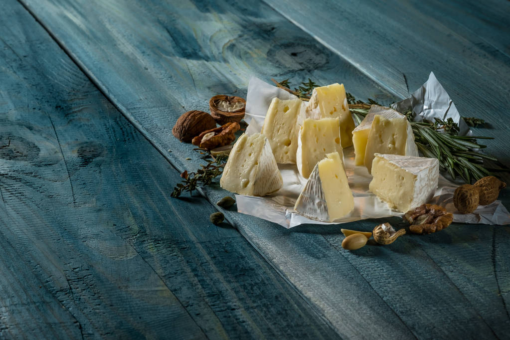 rodajas de queso camembert y nueces sobre fondo de madera azul, vista superior con espacio para copiar
 - Foto, Imagen