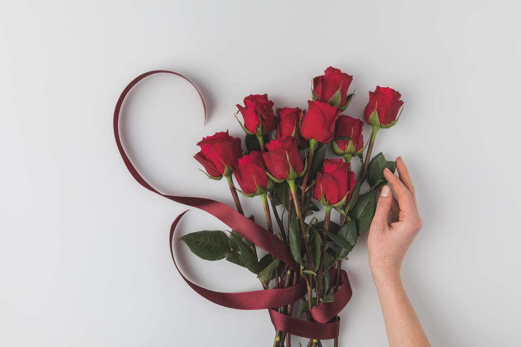 обрезанный снимок женской руки и букет красных роз с лентой на день Святого Валентина праздник изолирован на белом
 - Фото, изображение