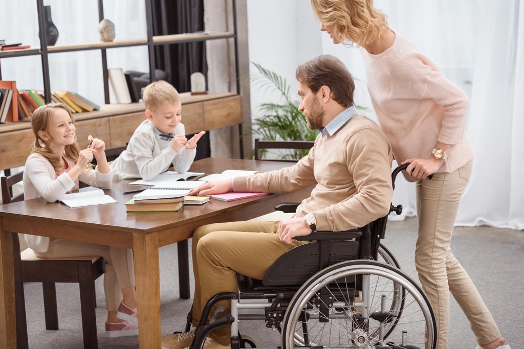 father on wheelchair and mother teaching kids at home - Photo, Image