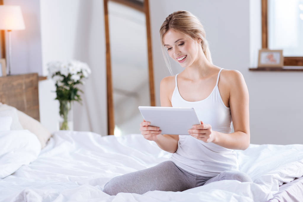 Mujer joven leyendo revista desde la tableta
 - Foto, imagen