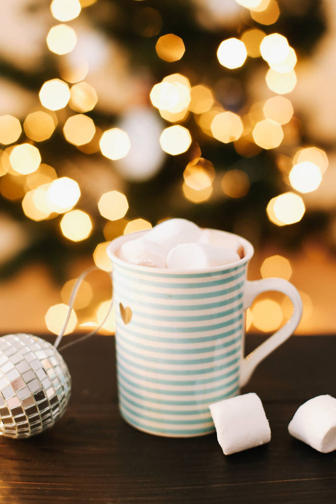 Різдвяна чашка кави з зефіром на фоні новорічних вогнів та прикрас
. - Фото, зображення