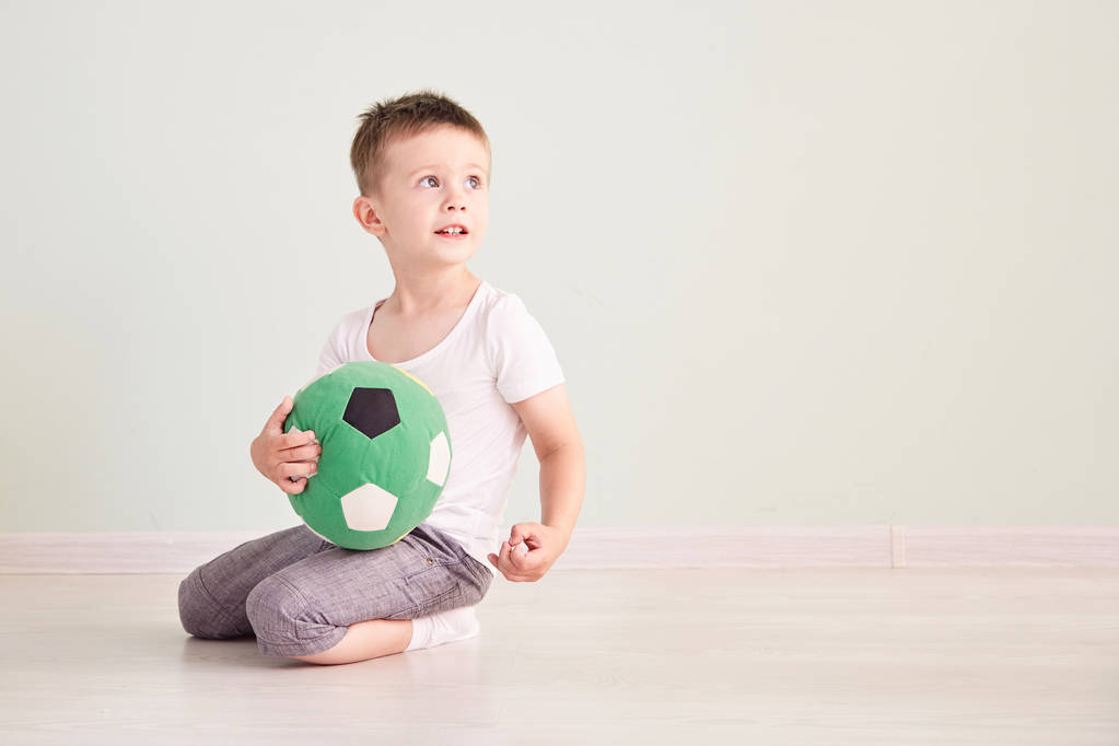 Ολόσωμο πορτρέτο του ένα παιδί με μια μπάλα ποδοσφαίρου απομονωμένη στο σπίτι - Φωτογραφία, εικόνα