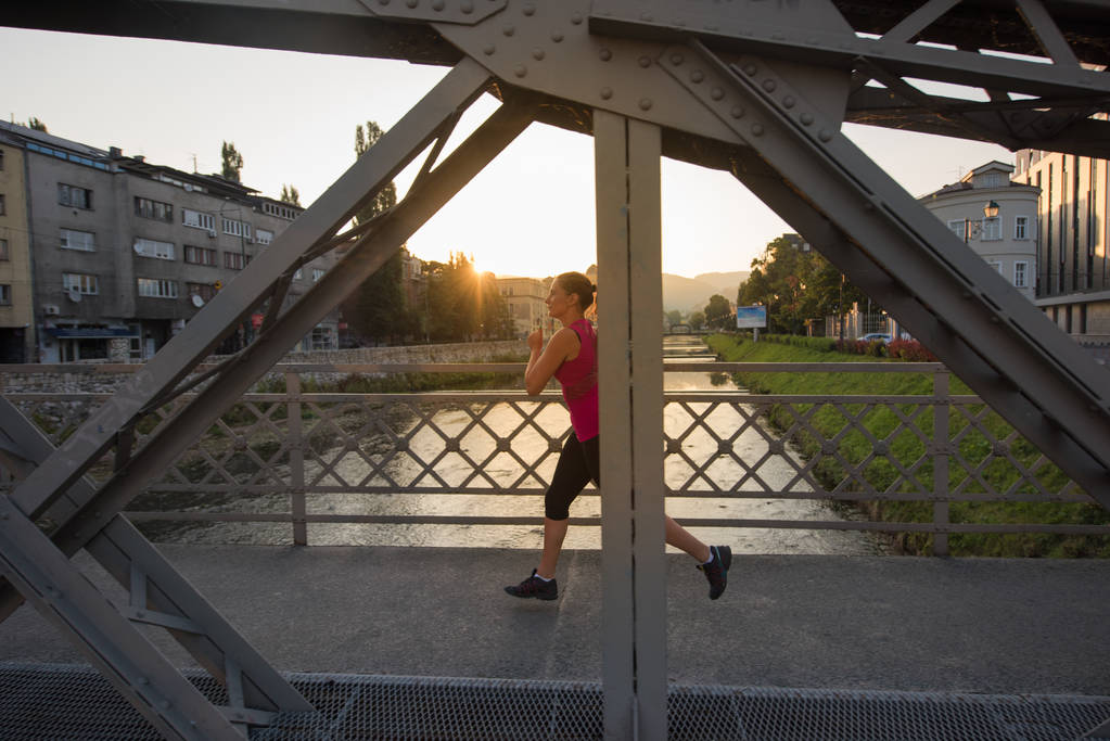 woman jogging across the bridge at sunny morning - Photo, Image