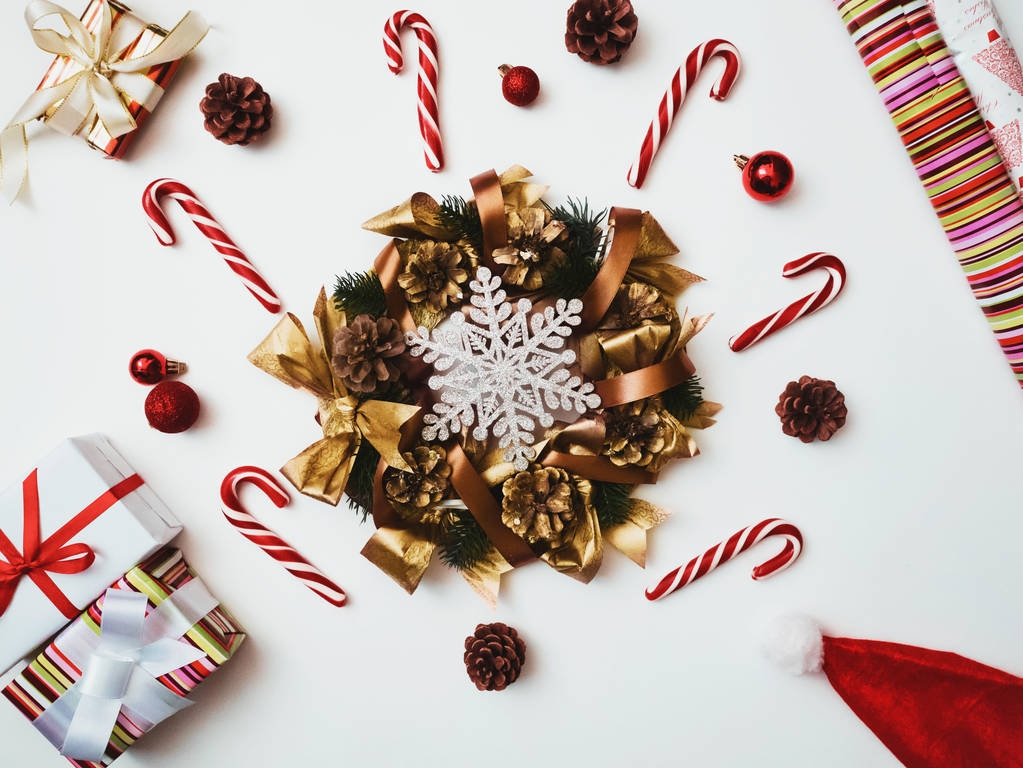 Pohled shora vánoční složení. Vánoční pozadí, věnec borovice, barevné dárkové krabice s červeným textilní páska, Santa čepice, třtiny lízátka, kužely, glitter zdobení snaowflake - Fotografie, Obrázek