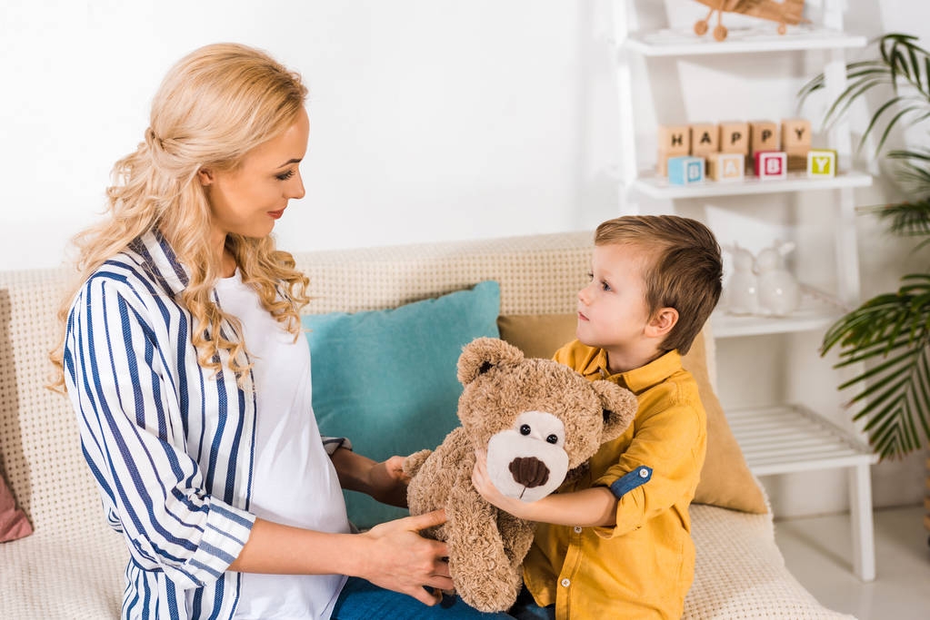 Schwangere Mutter präsentiert Sohn Teddybär - Foto, Bild