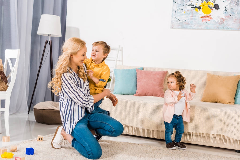 piękna i szczęśliwa matka i piękne małe dzieci, grając razem w domu - Zdjęcie, obraz