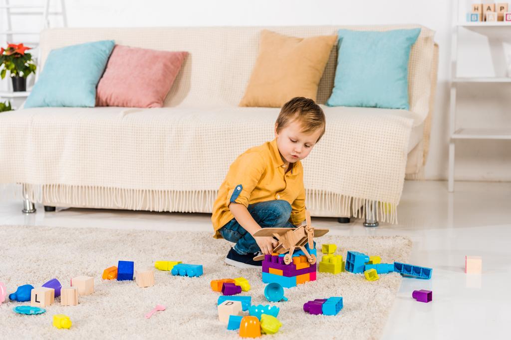 чарівний маленький хлопчик грає з іграшковим літаком і барвистими блоками вдома
 - Фото, зображення