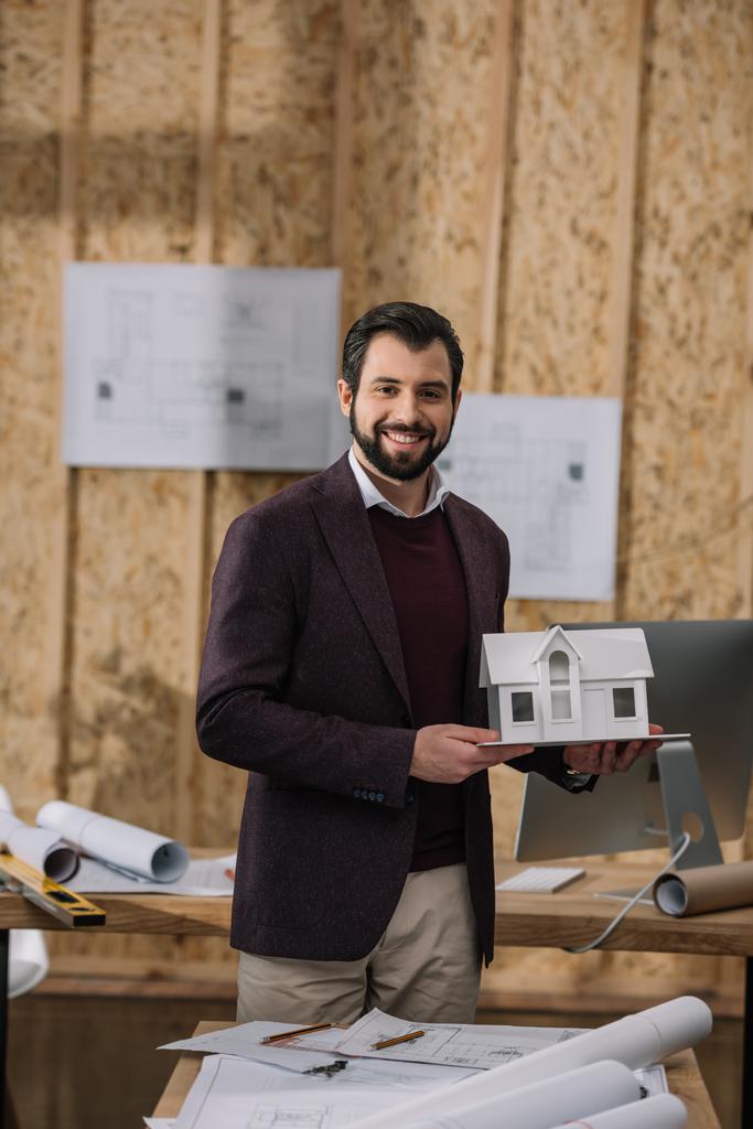 joven arquitecto con modelo de casa de papel en la oficina
 - Foto, Imagen