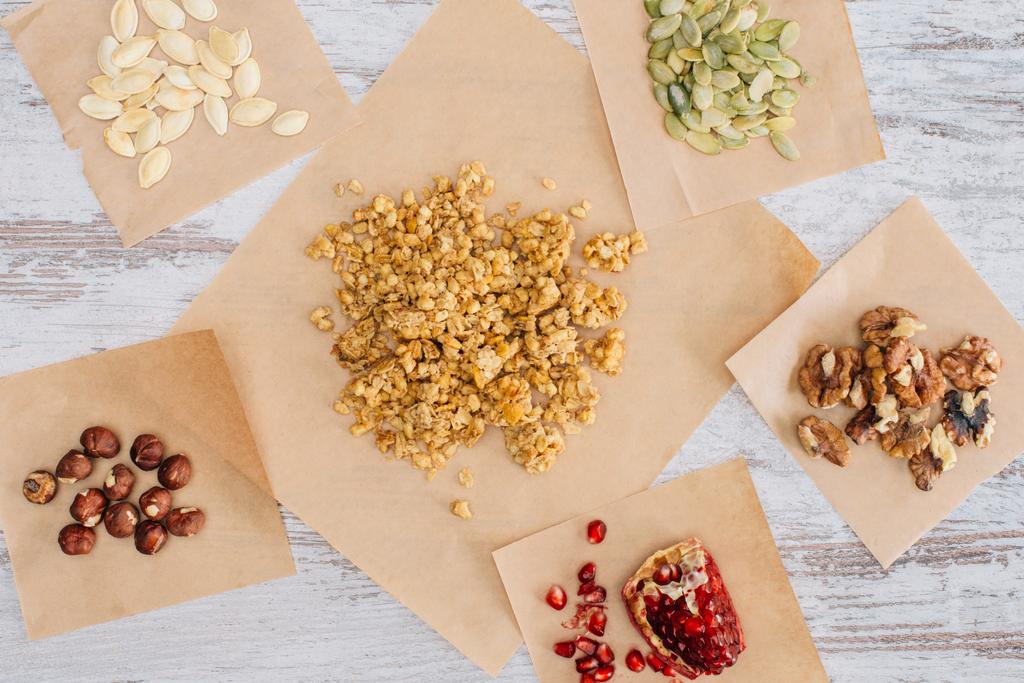 vista superior de ingredientes crocantes granola em pedaços de pergaminho de cozimento
 - Foto, Imagem