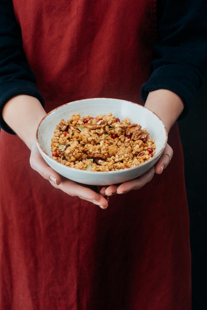 imagen recortada de cocinera hembra sosteniendo tazón con granola
 - Foto, Imagen