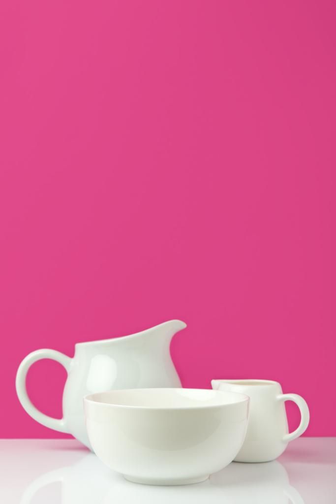 vista close-up de tigela branca vazia, jarro grande e jarro de leite em rosa
  - Foto, Imagem