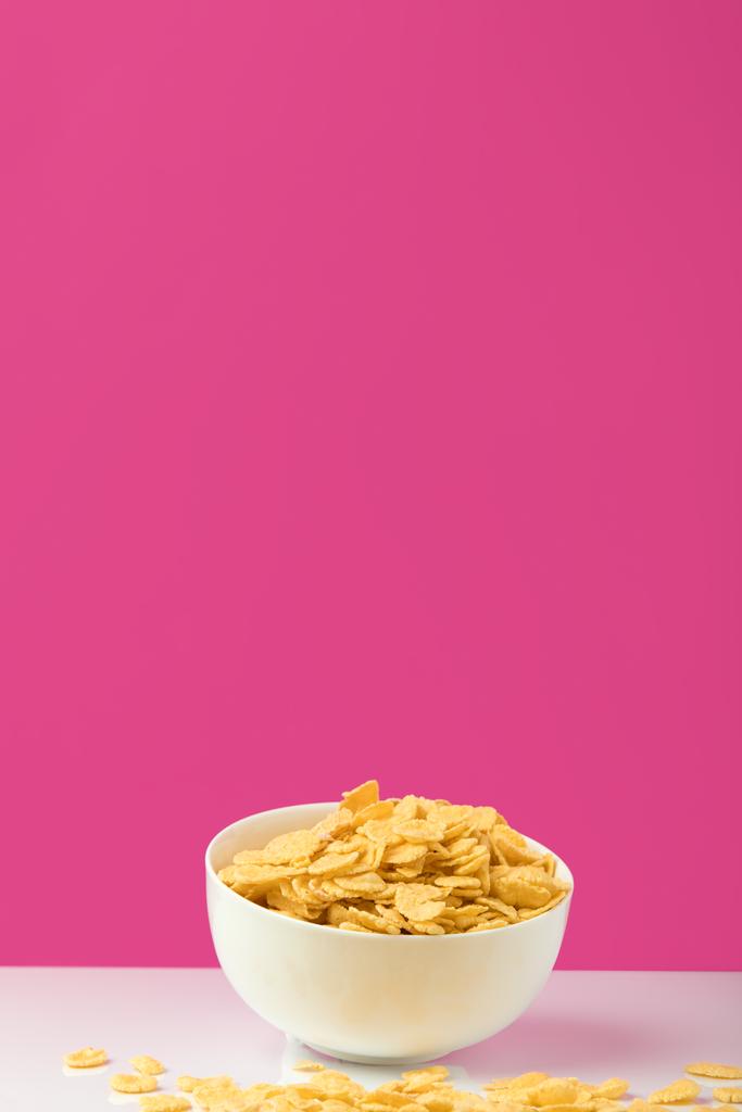 vergrote weergave van witte kom vol zoete smakelijke cornflakes op roze      - Foto, afbeelding