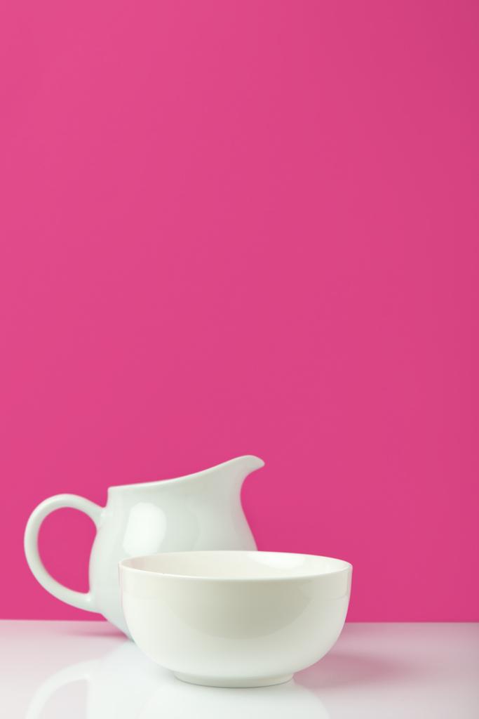 close-up view of empty white bowl and jug on pink  - Photo, Image