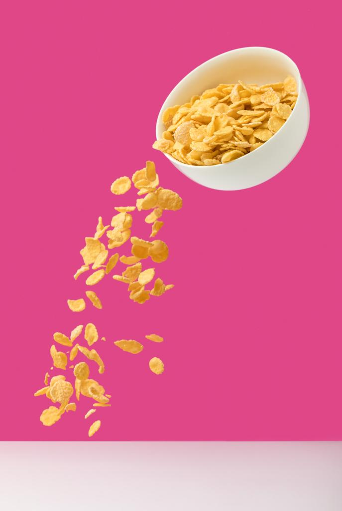 tazón blanco con hojuelas de maíz vertiendo en rosa
  - Foto, imagen