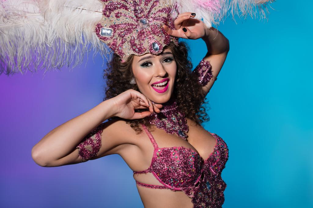 Veselá žena v karnevalový kostým růžové peří izolované na modrém pozadí - Fotografie, Obrázek