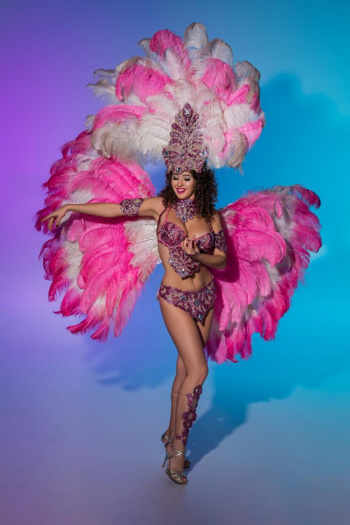 Яркая женщина в карнавальном костюме с розовыми перьями на синем фоне
 - Фото, изображение