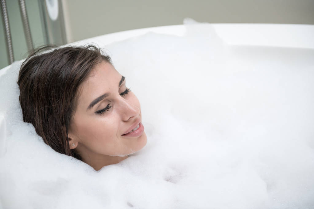 Hermosa mujer blanca joven disfrutar de relajarse en baño de burbujas. Descansando, con los ojos cerrados. Mujer blanca caucásica
. - Foto, Imagen