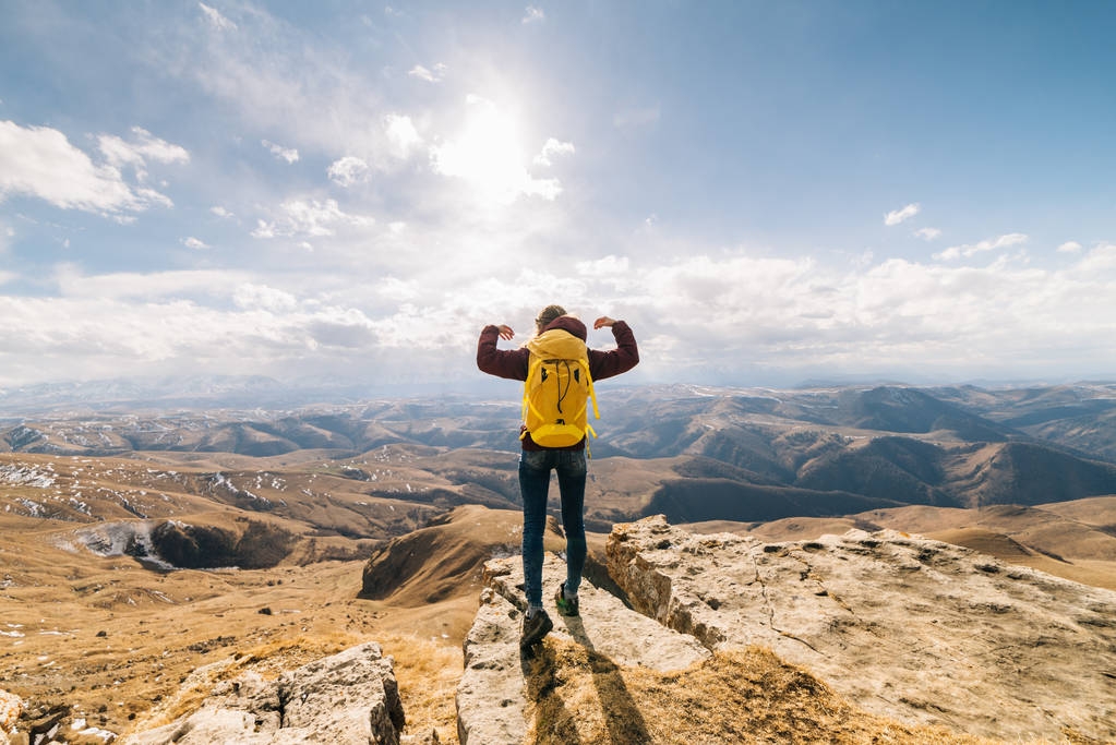 jong meisje, een toerist met een gele rugzak tegen een achtergrond van zonnige landschap in de bergen - Foto, afbeelding