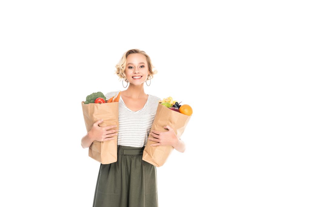 jeune femme tenant des sacs en papier avec des fruits et légumes et souriant à la caméra isolée sur blanc
 - Photo, image